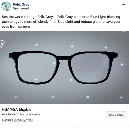 A pair of eyeglasses with blue light reflections on the lenses, displayed against a gray background with small blue light spots.